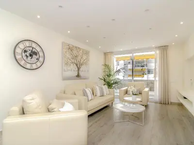 a living room with white furniture and a clock on the wall at Sitges Spaces Oasis Suites- 4 Bedroom, 4 Ensuite Bathrooms, Terrace, Pool, Sitges Centre in Sitges