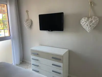 a bedroom with a tv on the wall and a dresser at Karin Palma Fiesta-Vallpineda-Sitges in Sant Pere de Ribes