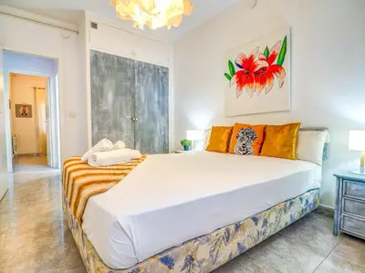 a bedroom with a large white bed with orange pillows at The Beach Holi Apartment by Hello Homes Sitges in Sitges