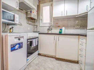 a kitchen with white cabinets and a sink at The Beach Holi Apartment by Hello Homes Sitges in Sitges