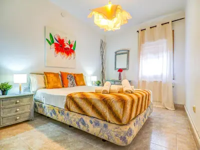 a bedroom with a large bed and a chandelier at The Beach Holi Apartment by Hello Homes Sitges in Sitges