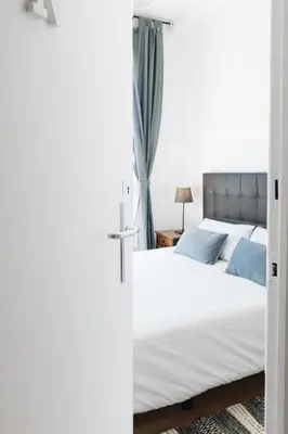 a bedroom with a bed with white sheets and blue pillows at Sunny and modern apartment ideal for groups in Barcelona