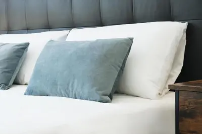 a bed with white pillows and a blue pillow at Sunny and modern apartment ideal for groups in Barcelona