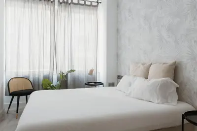 a white bedroom with a large white bed and a window at Apartamentos Espai Progres by Be Barcelona in Hospitalet de Llobregat