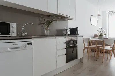 a kitchen with white cabinets and a table with chairs at Apartamentos Espai Progres by Be Barcelona in Hospitalet de Llobregat