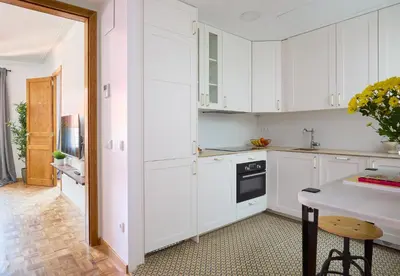 a white kitchen with white cabinets and a table at Casa Cosi - El Farro 3 in Barcelona