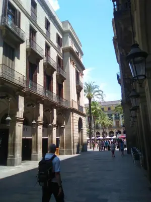 a man with a backpack walking down a street next to a building at Colom Apartments in Barcelona