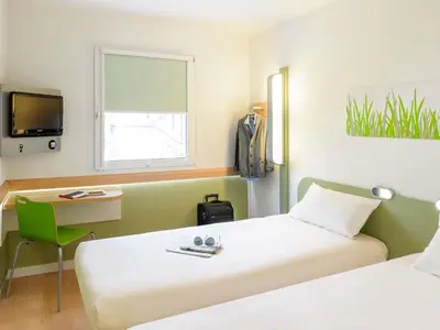 a hotel room with a large white bed and a couch at Ibis Budget Barcelona Sant Andreu De La Barca in Sant Andreu de la Barca