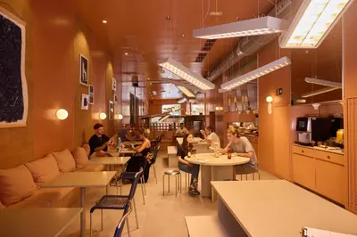 a group of people sitting at tables in a restaurant at Latroupe Poblenou Beach in Barcelona