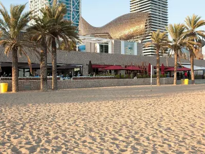 a beach with palm trees in front of a building at Ibis Budget Barcelona Viladecans in Viladecáns
