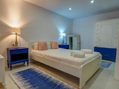 a bedroom with a large bed with a nightstand and a mirror at Villa Elysian by Hello Homes Sitges in Sant Pere de Ribes