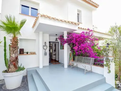 a white house with pink flowers and a bench at Villa Elysian by Hello Homes Sitges in Sant Pere de Ribes