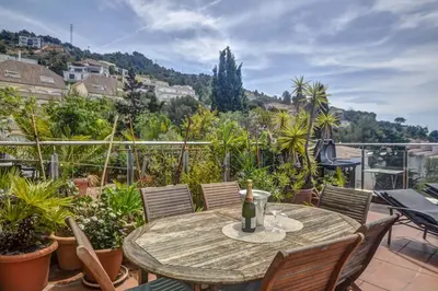 a table with a bottle of wine on a balcony at Tropical Terrace Apartment by Hello Homes Sitges in Sitges