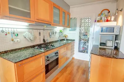 a kitchen with wooden cabinets and a stove top oven at Tropical Terrace Apartment by Hello Homes Sitges in Sitges