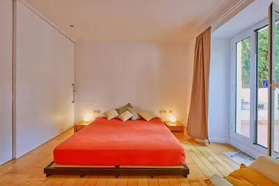 a bedroom with a red bed and a large window at Casa de Pueblo junto Barcelona Centro in Vilassar de Dalt