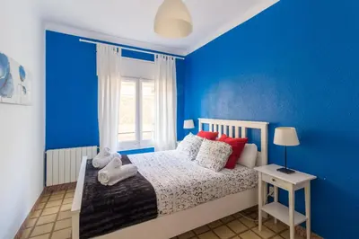a blue bedroom with a bed and a window at rentBCN City Center Apartment in Barcelona