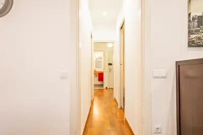 a hallway with white walls and a wooden floor at Alcam Enamorats in Barcelona