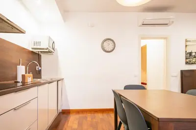 a kitchen with a table and a clock on the wall at Alcam Enamorats in Barcelona