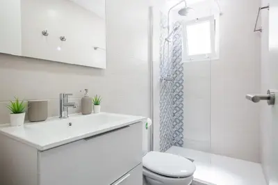 a white bathroom with a toilet and a sink at Blau Atic Apartment in Barcelona