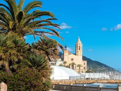 a church on the beach with palm trees at Apartment Primer de Maig by Interhome in Sitges