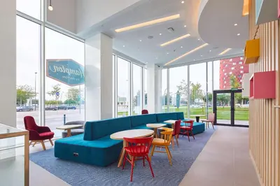 a lobby with a blue couch and tables and chairs at Hampton By Hilton Barcelona Fira Gran Via in Hospitalet de Llobregat