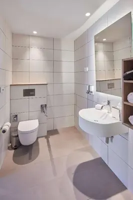 a white bathroom with a toilet and a sink at Hampton By Hilton Barcelona Fira Gran Via in Hospitalet de Llobregat
