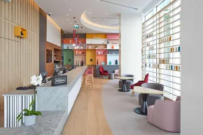 a lobby of a library with tables and chairs at Hampton By Hilton Barcelona Fira Gran Via in Hospitalet de Llobregat