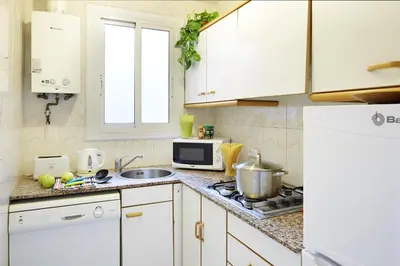 a kitchen with white cabinets and a stove top oven at Apartamentos Calvet in Barcelona