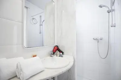 a white bathroom with a sink and a shower at Apartamentos Calvet in Barcelona