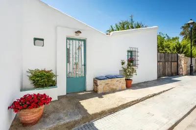 a white house with a blue door and flowers at Apartamento rústico reformado con encanto (Garraf) in Sant Pere de Ribes