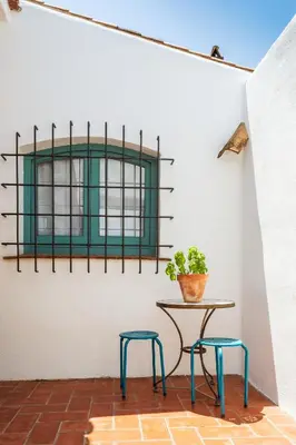 a table and two stools in a room with a window at Apartamento rústico reformado con encanto (Garraf) in Sant Pere de Ribes