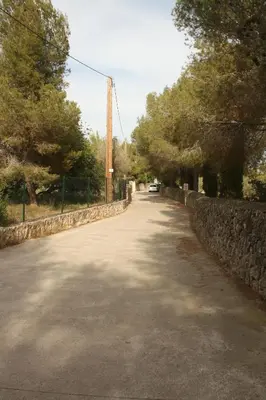 an empty road with a stone wall and trees at Apartamento rústico reformado con encanto (Garraf) in Sant Pere de Ribes