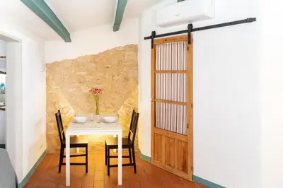 a dining room with a table and chairs and a door at Apartamento rústico reformado con encanto (Garraf) in Sant Pere de Ribes
