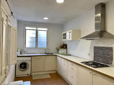 a kitchen with white cabinets and a washer and dryer at El masnou in Masnou
