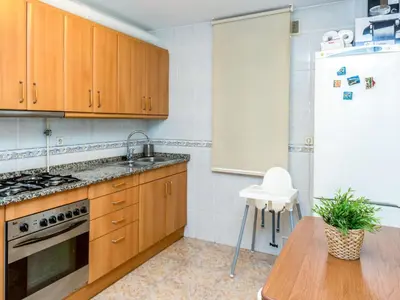a kitchen with wooden cabinets and a sink and a table at Apartment Camp Nou by Interhome in Barcelona
