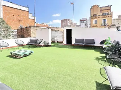 a patio with green grass and chairs on a building at Casa nanit apt b in Hospitalet de Llobregat
