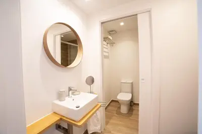 a bathroom with a sink and a mirror and a toilet at Apartaments Voralmar in Caldes d'Estrac