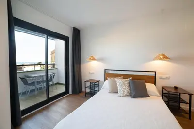 a bedroom with a large bed and a balcony at Apartaments Voralmar in Caldes d'Estrac