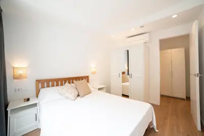 a white bedroom with a white bed and a room at Apartaments Voralmar in Caldes d'Estrac