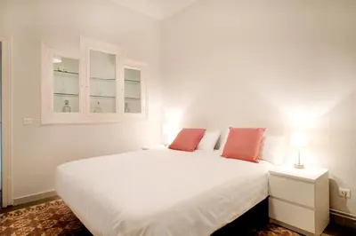 a white bed in a white room with two lamps at Casa Valeta in Barcelona