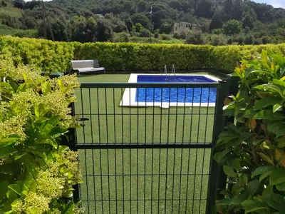 a black fence with a pool in a garden at Apartamento Arenys de Munt - Costa Barcelona, Maresme - in Arenys de Munt