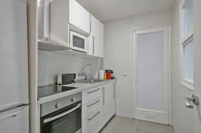 a white kitchen with a sink and a microwave at Habitat Apartments Plaza España Urban in Barcelona