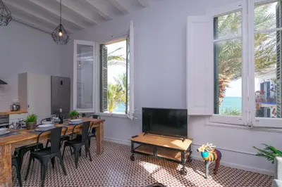 a dining room with a table and chairs and the ocean at 1840 Apartments Sitges by Suma Hotels in Sitges