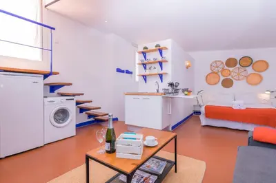 a living room with a couch a table and a kitchen at 1840 Apartments Sitges by Suma Hotels in Sitges