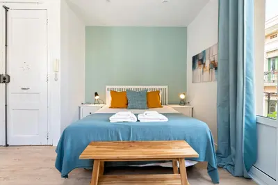 a bedroom with a bed with a blue blanket and a table at Lodging Apartments Barceloneta Beach Studio 31 in Barcelona