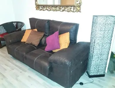 a brown leather couch with colorful pillows on it at Apartamento Sagrada Familia in Barcelona