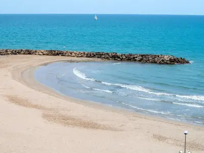 a sandy beach with a boat in the ocean at Apartment Sun and Beach by Interhome in Cunit