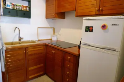 a kitchen with a white refrigerator and wooden cabinets at Fragata Beach Seaview in Sitges