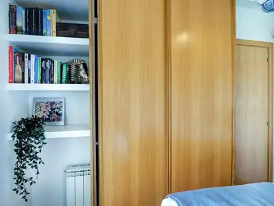 a bedroom with a wooden cabinet with books at Los Condes Penthouse by Hello Homes Sitges in Sitges