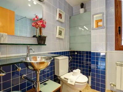 a blue tiled bathroom with a sink and a toilet at Los Condes Penthouse by Hello Homes Sitges in Sitges